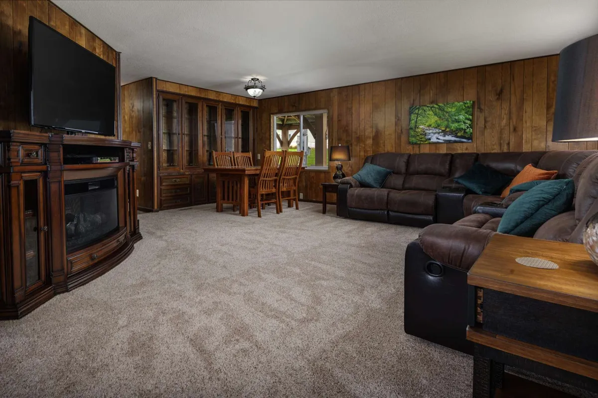 A view of a warm, inviting space with a large TV, a comfortable sofa, and a wooden dining table. The setup is perfect for both entertainment and family gatherings, providing a seamless blend of leisure and dining activities.